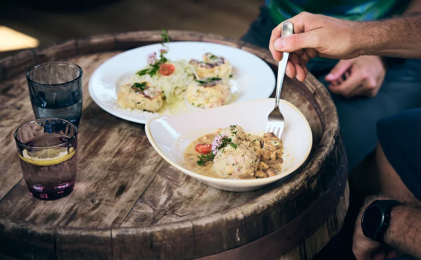Mann isst traditionelle Knödel mit Soße an einem Holztisch