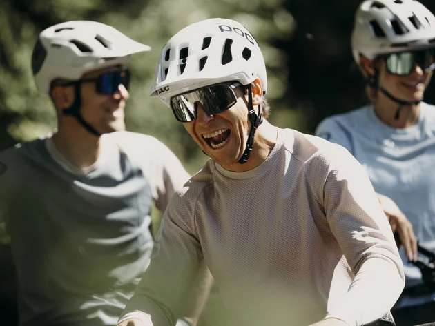 Was steckt hinter dem Umweltengagement von Bikehotels? Drei lächelnde Radfahrer mit Helmen und Sonnenbrillen im Freien