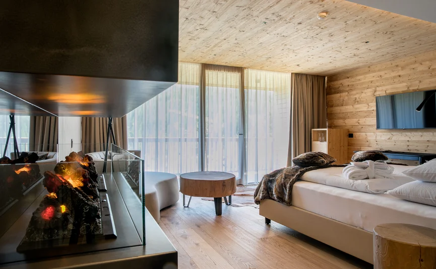 Modern hotel room with fireplace, wooden floor and balcony with curtains
