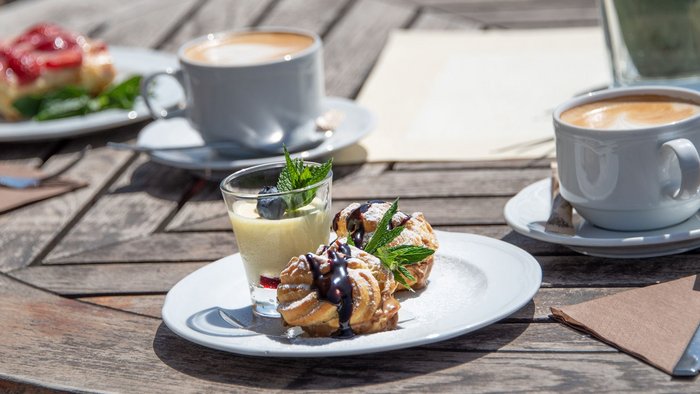 Kaffee und verschiedene Desserts auf einem Holztisch im Freien