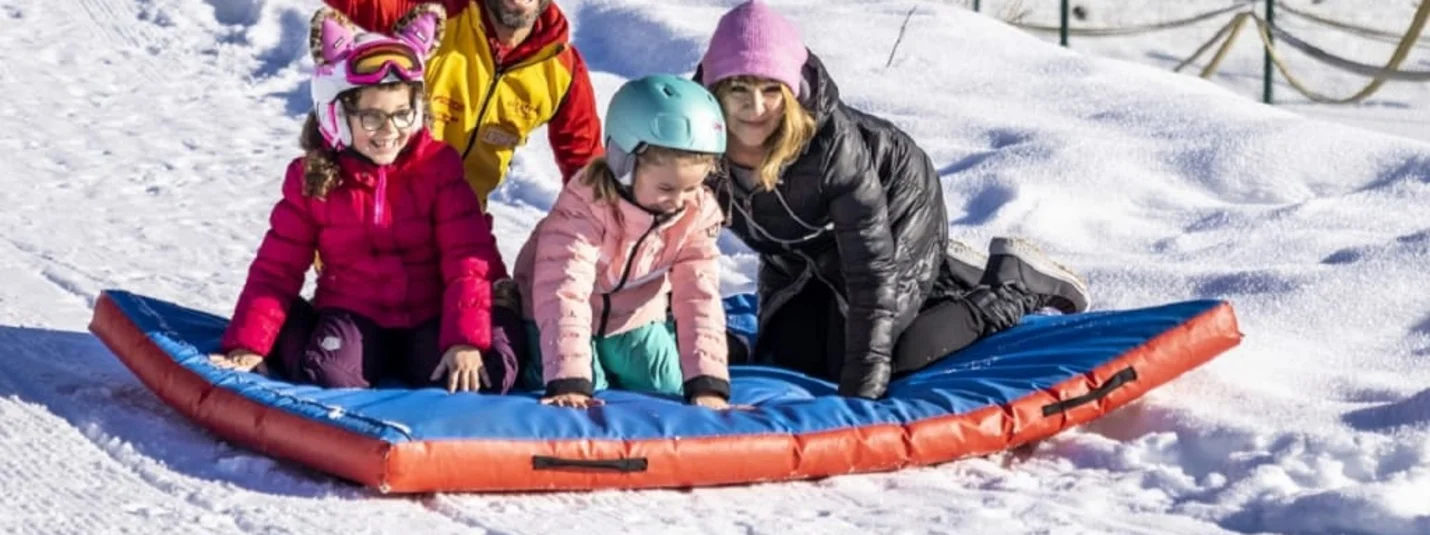 Family riding together on an inflatable sled through the snow