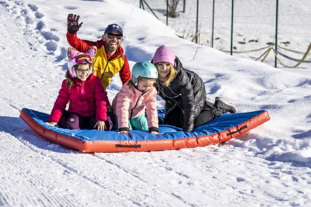 Family riding together on an inflatable sled through the snow