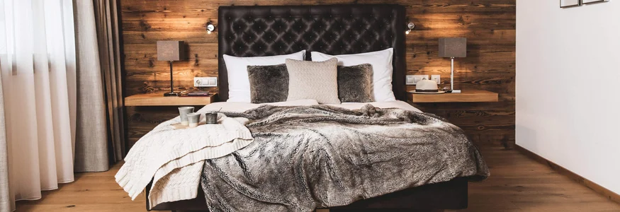 Biken & Genießen im Montanara © Anja Koppitsch Photography Gemütliches Schlafzimmer mit Holzwänden und einem großen Bett mit Decken