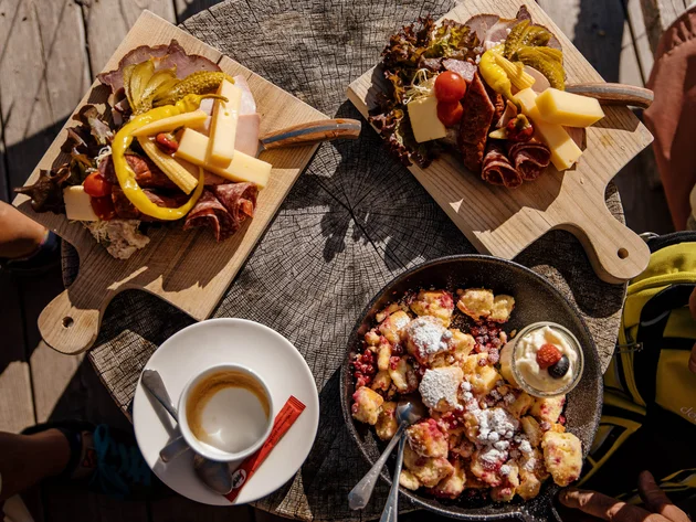 Houten plankjes met kaas en vlees, Kaiserschmarrn en espresso op houten tafel