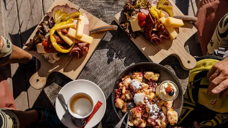 Houten plankjes met kaas en vlees, Kaiserschmarrn en espresso op houten tafel