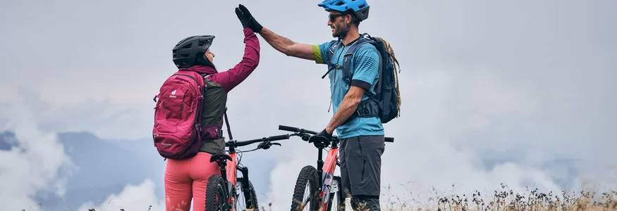 Zwei Mountainbiker geben sich auf einer Wiese einen High Five