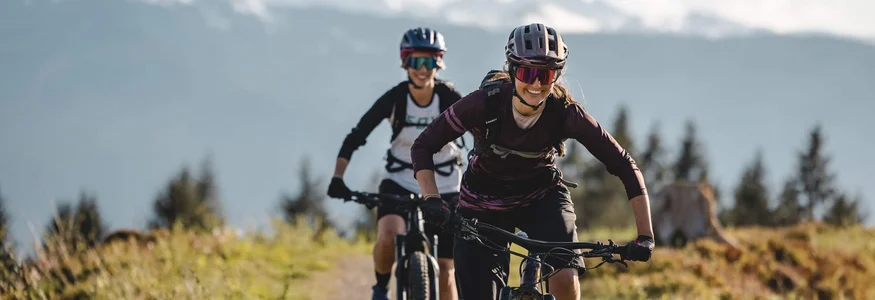 Welcher Hohe Salve-MTB-Typ bist du? © Mathäus Gartner Zwei Frauen fahren Mountainbike auf Bergpfad mit Bergen im Hintergrund