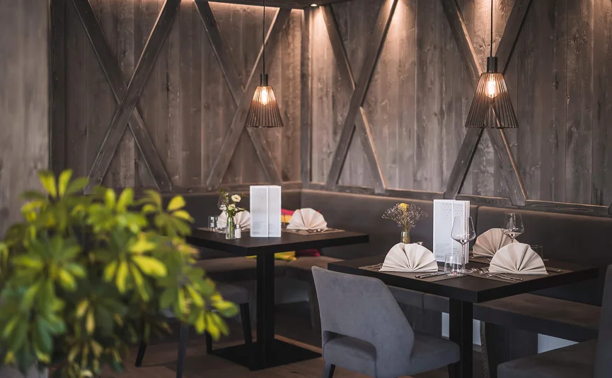 HIRBEN Naturlaub **** © Manuel Kottersteger Set tables in a modern restaurant with soft lighting and wooden walls