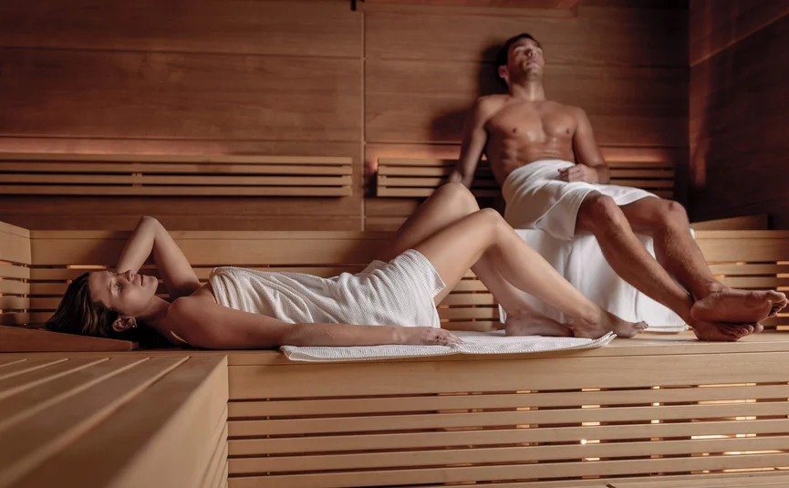 Mann und Frau entspannen in einem hölzernen Saunaraum