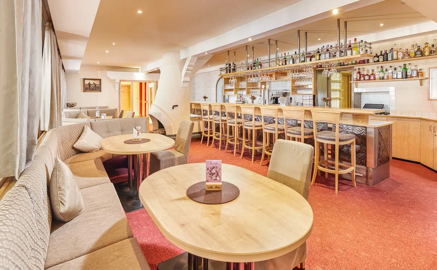 Cozy bar with wooden counter, benches, and tables in warm lighting