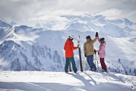 SUPER SKI Days Three skiers on snowy mountain peak giving a high-five