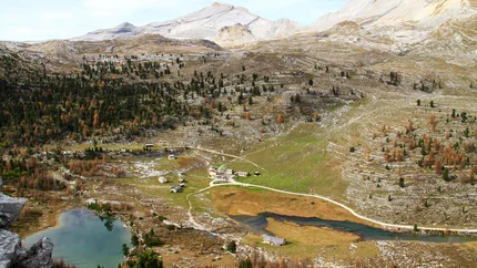 Berglandschaft mit kleinem See, Wegen und vereinzelten Häusern im Tal