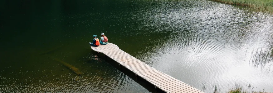 Zwei Radfahrer sitzen auf einem Steg über einem See in der Natur