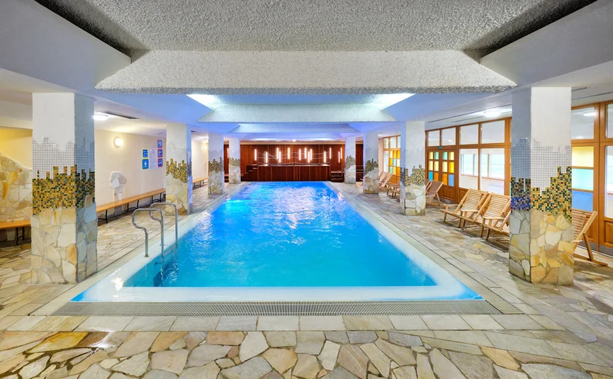 Overdekt verwarmd zwembad met ligstoelen en mozaïekpilaren