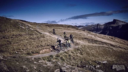 Vijf mountainbikers rijden op een pad in alpien berglandschap