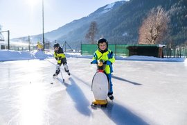 Wintertage 5=4 Twee kinderen spelen ijshockey op een buitenbaan in de bergen