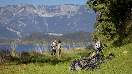 Fietsen en rugzak op gras met twee wandelaars en bergen op de achtergrond