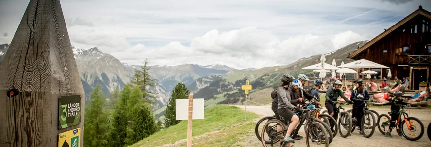 Gruppe von Mountainbikern startet auf Bergpfad in alpiner Landschaft