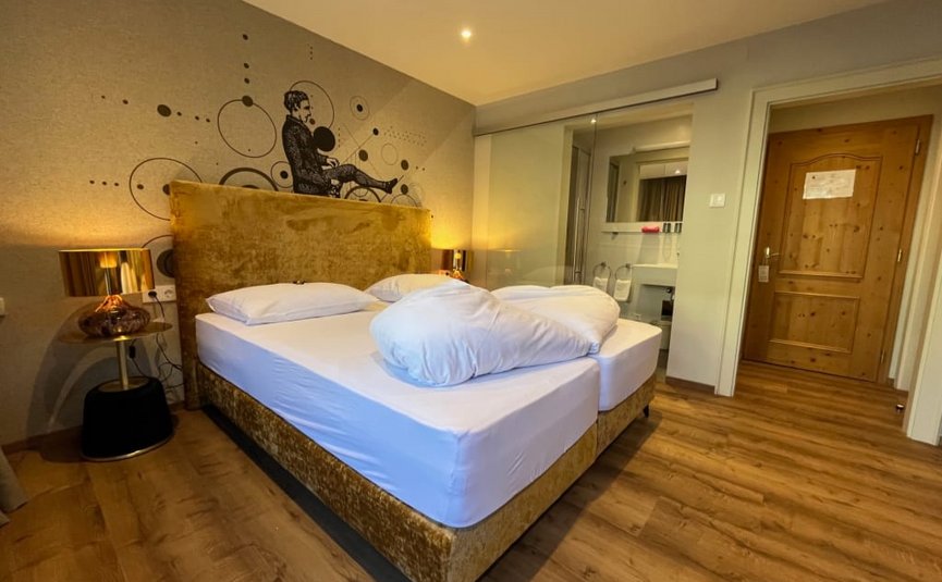 Hotelzimmer mit Doppelbett, Holzboden und Wandkunst hinter dem Bett