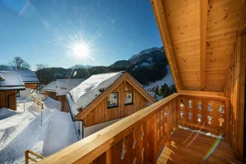 Ski Woche 7 Nächte inkl. Skipass Verschneite Holzhäuser und Berge, gesehen von einem sonnigen Holzbalkon