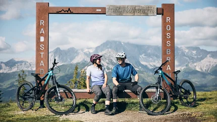 Flachau Cycling Region – from cycling adventures to signature rides © Tobias Köhler Two cyclists sitting by bikes at a mountain view frame in Radstadt Rossbrand.