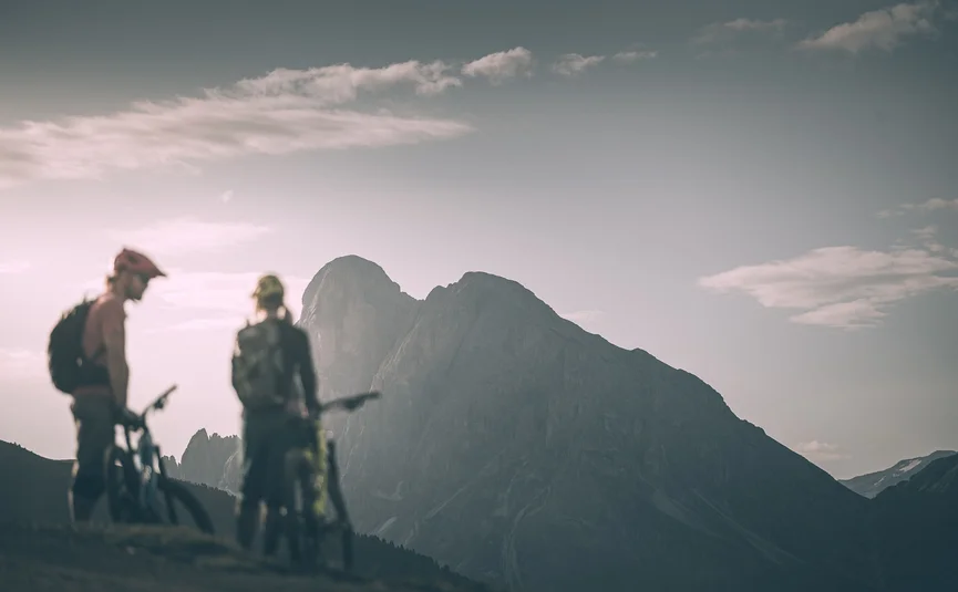 Zwei Radfahrer auf Bergweg mit felsigem Berg im Hintergrund