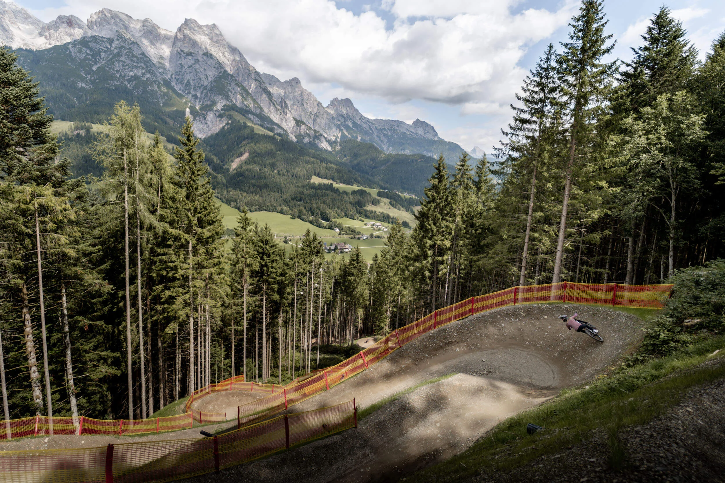 Happy Birthday EPIC Bike Park! © Yvonne Hörl Fahrradfahrer fährt auf kurvenreichem Waldweg mit Bergblick