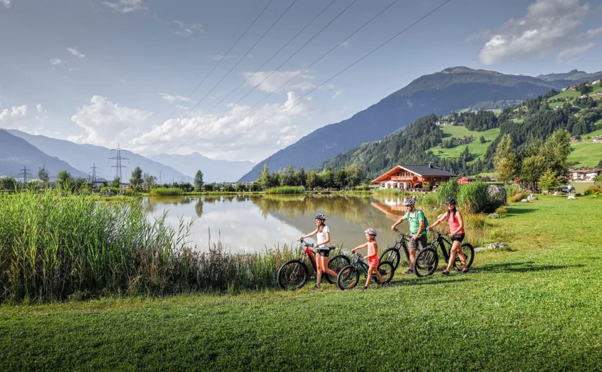 Familie mit Fahrrädern nahe See und Bergen bei Sonnenschein