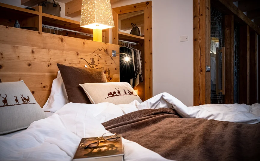 Cozy bedroom with wood accents and a lit bedside lamp in mountain style