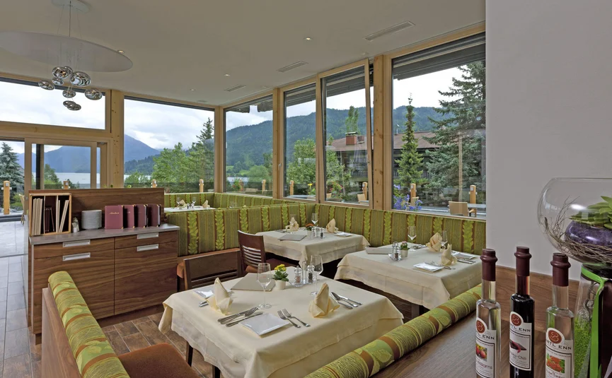 Gemütliches Restaurant mit grünen Sitzbänken und Bergblick durch große Fenster.
