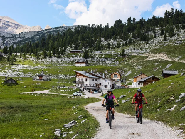 Ein Herbst-Wochenende in San Vigilio © Norman Bielig Zwei Mountainbiker auf Bergweg vor Almhütte und bewaldetem Gebirge