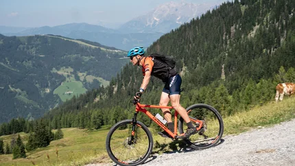 Cyclist rides on mountain path with mountains in background