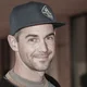 Mann mit schwarzer Baseballkappe lächelt in Innenraum