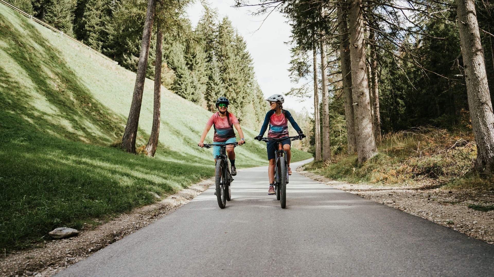 Zwei Personen fahren mit Mountainbikes auf Waldweg