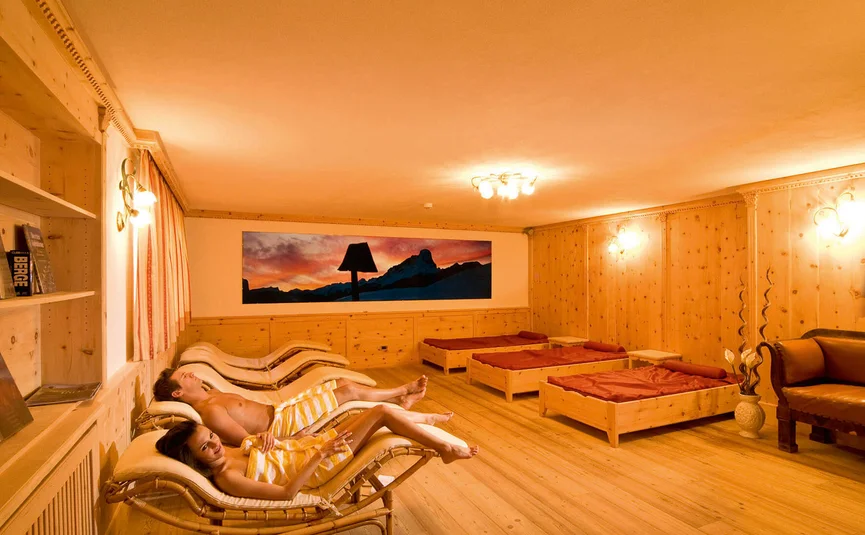Entspannter Mann und Frau liegen in Holzsauna-Lounge auf Liegestühlen