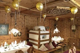 Ski, Gourmet & Dorfsilvester Rustieke eetzaal met houten lambrisering, gedekte tafels en gouden ballonnen