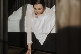 Frau liegt auf Bett und greift nach Buch auf Boden