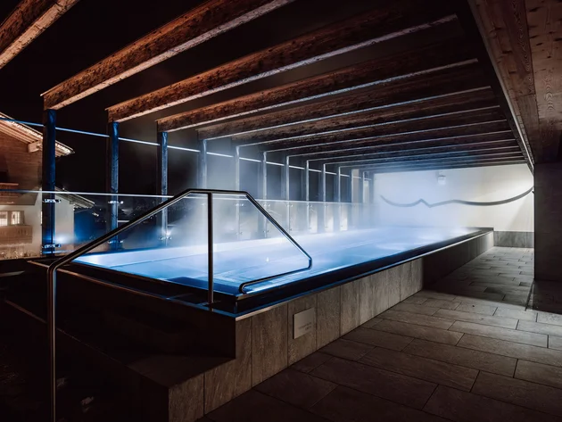 Bike & Wellness Heated outdoor pool with wooden roof structure and steam at night