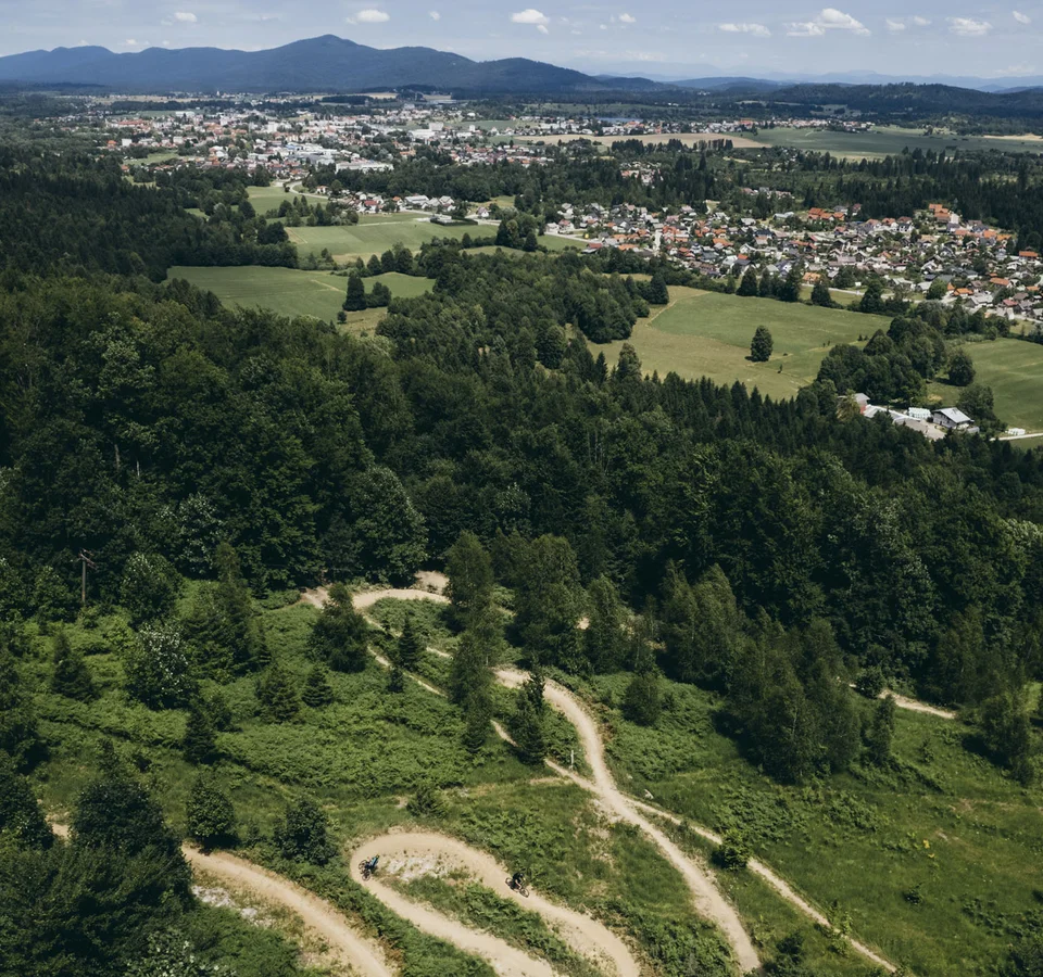 9 Gründe, warum Kočevsko noch ein echter MTB-Geheimtipp ist
© Klemen Humar - MTBTrailCenter Luftaufnahme eines Waldgebietes mit Wanderwegen und Stadt in der Ferne