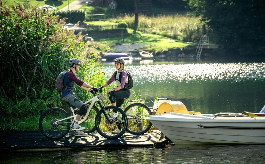 Bike Boutique Hotel Lindenhof **** Two cyclists with helmets by the lake next to a boat on a sunny day