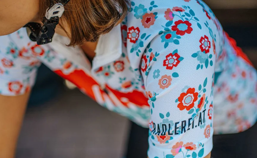Ladylike Radmarathon Package - 2 Nächte Frau trägt floral gemustertes Trikot mit text padler.at auf dem Ärmel