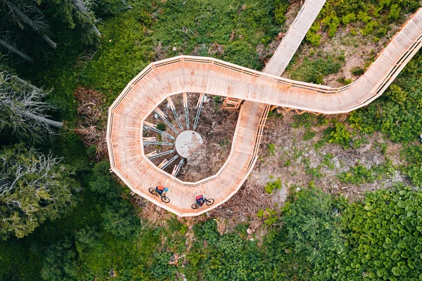 Singletrails © Patrick Wasshuber Fietsers op spiraalvormige houten brug in groen bos