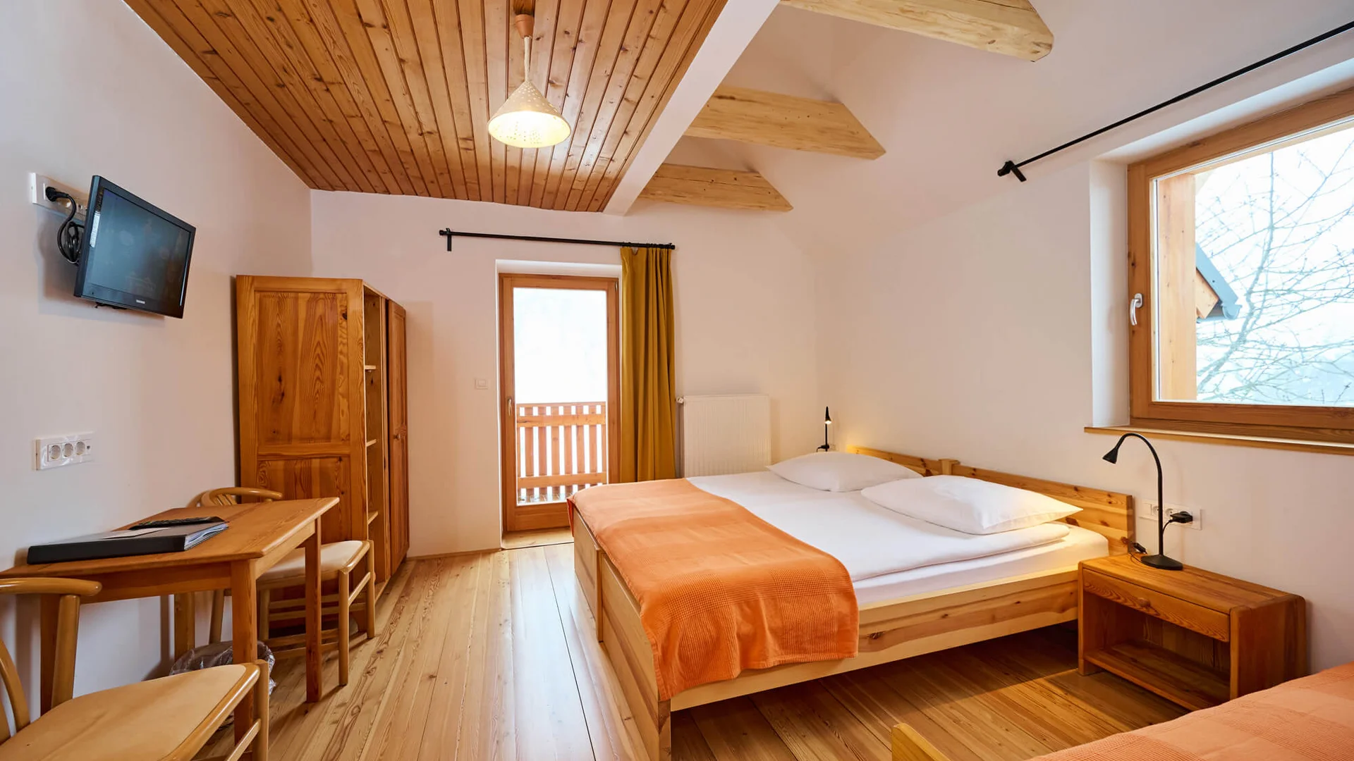 Hell eingerichtetes Schlafzimmer mit Holzmöbeln und orangen Bettdecken