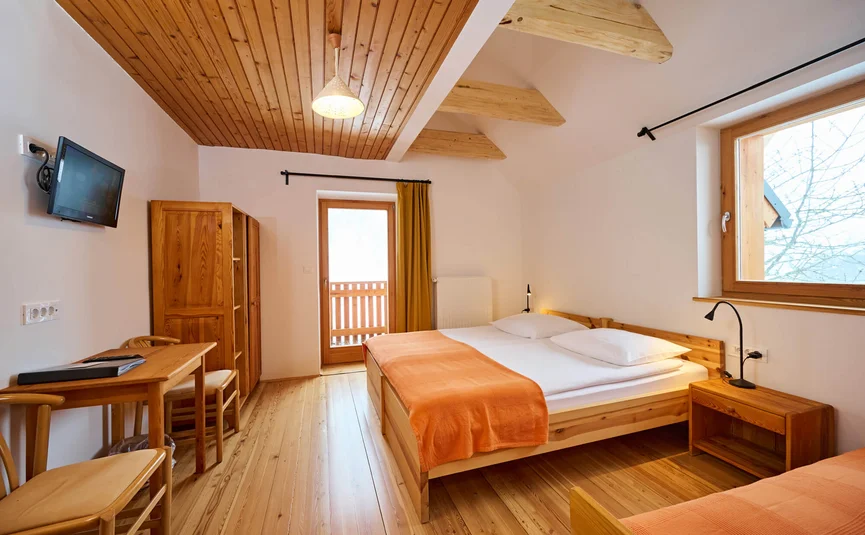 Hell eingerichtetes Schlafzimmer mit Holzmöbeln und orangen Bettdecken