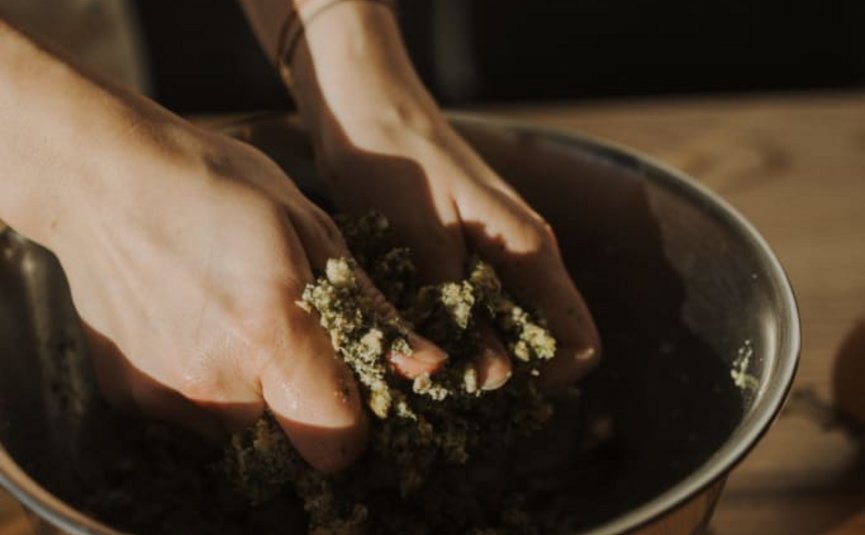 Hände kneten Kräutermischung in einer Metallschüssel