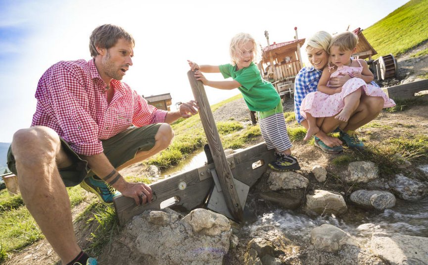 FAMILY PACKAGE Family playing by a stream with wooden sluice on a sunny day
