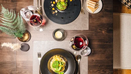 Elegantes Abendessen mit Wein, Pasta und Salat auf dunklem Holztisch