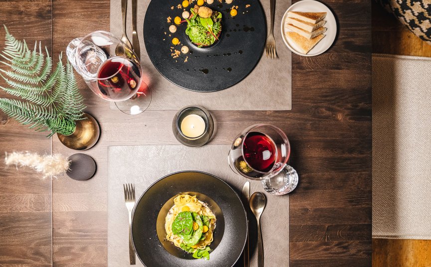 Hotel Arpuria | Hidden Luxury Mountain Home **** © Brandnamic Elegantes Abendessen mit Wein, Pasta und Salat auf dunklem Holztisch