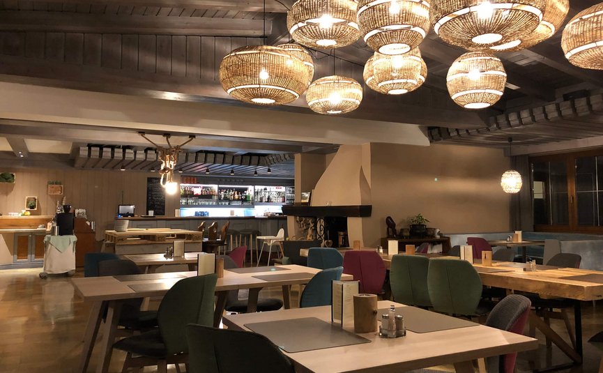 Gemütliches Restaurant mit hölzernen Tischen, bunten Stühlen und dekorativen Lampen