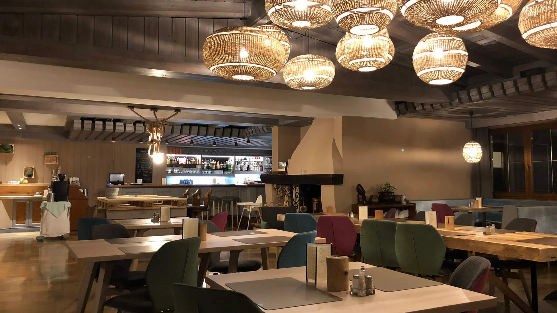 Gemütliches Restaurant mit hölzernen Tischen, bunten Stühlen und dekorativen Lampen